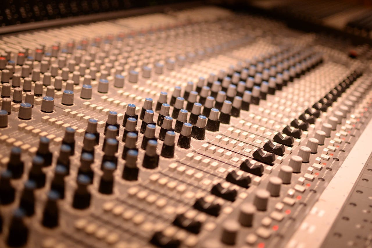 about-04 Detailed view of an analog audio mixing console with various knobs and sliders in a sound studio.